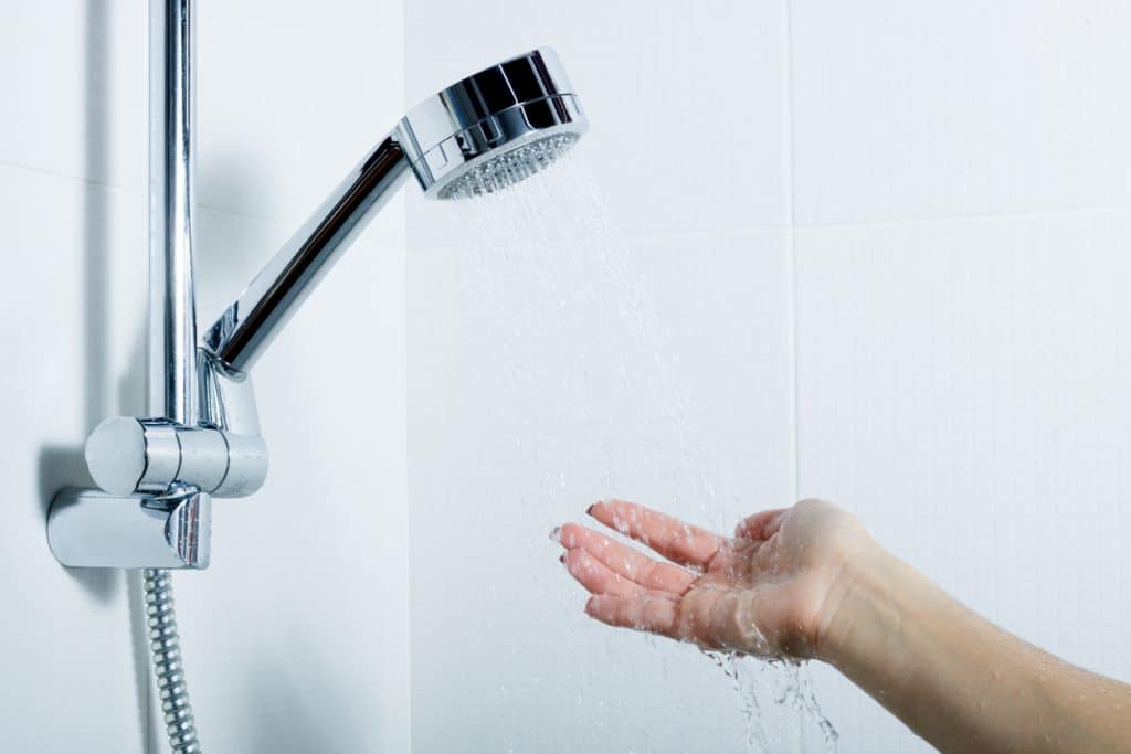 Hand reaches into shower water